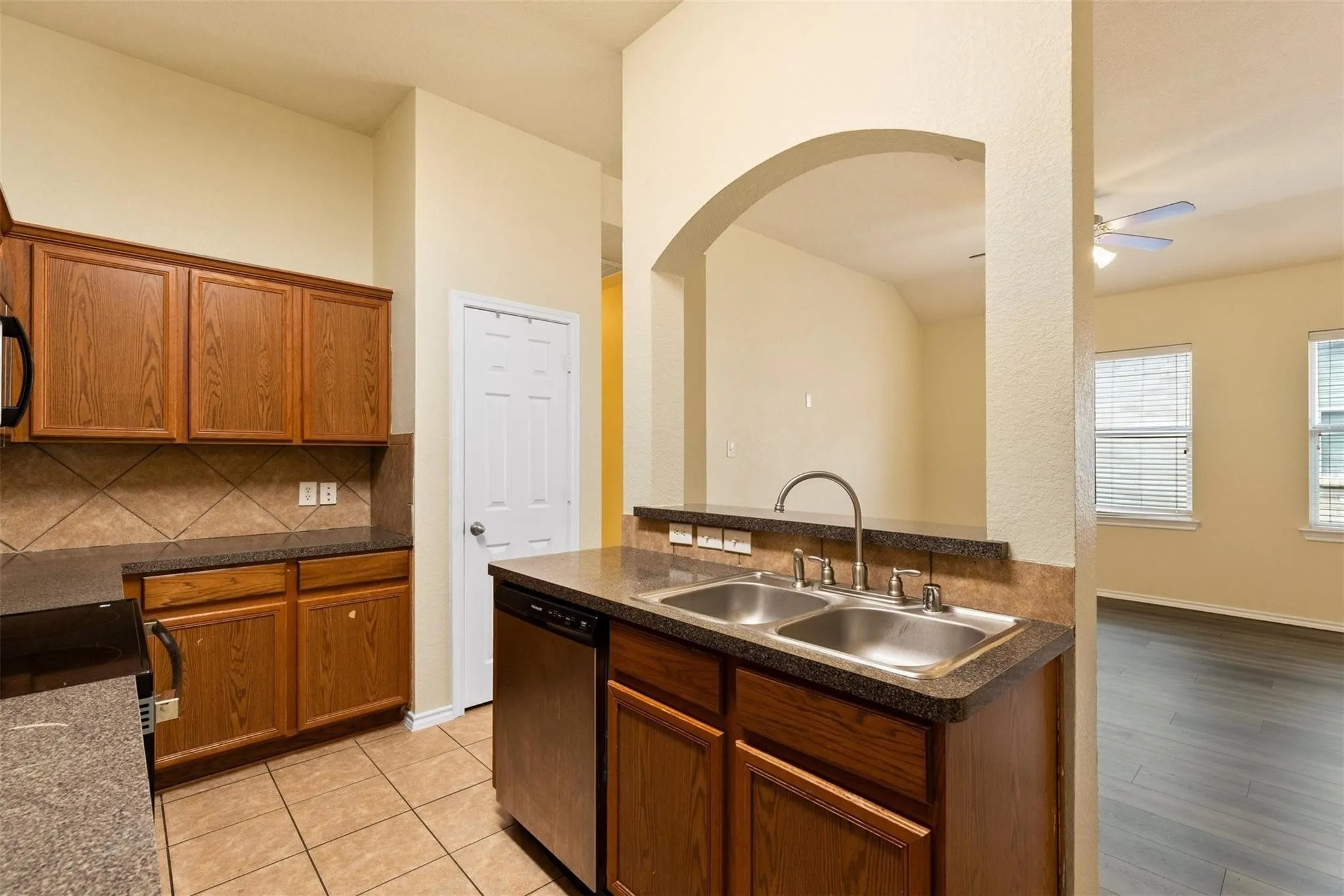Kitchen with wood cabinetry, tiled backsplash, and dual basin sink