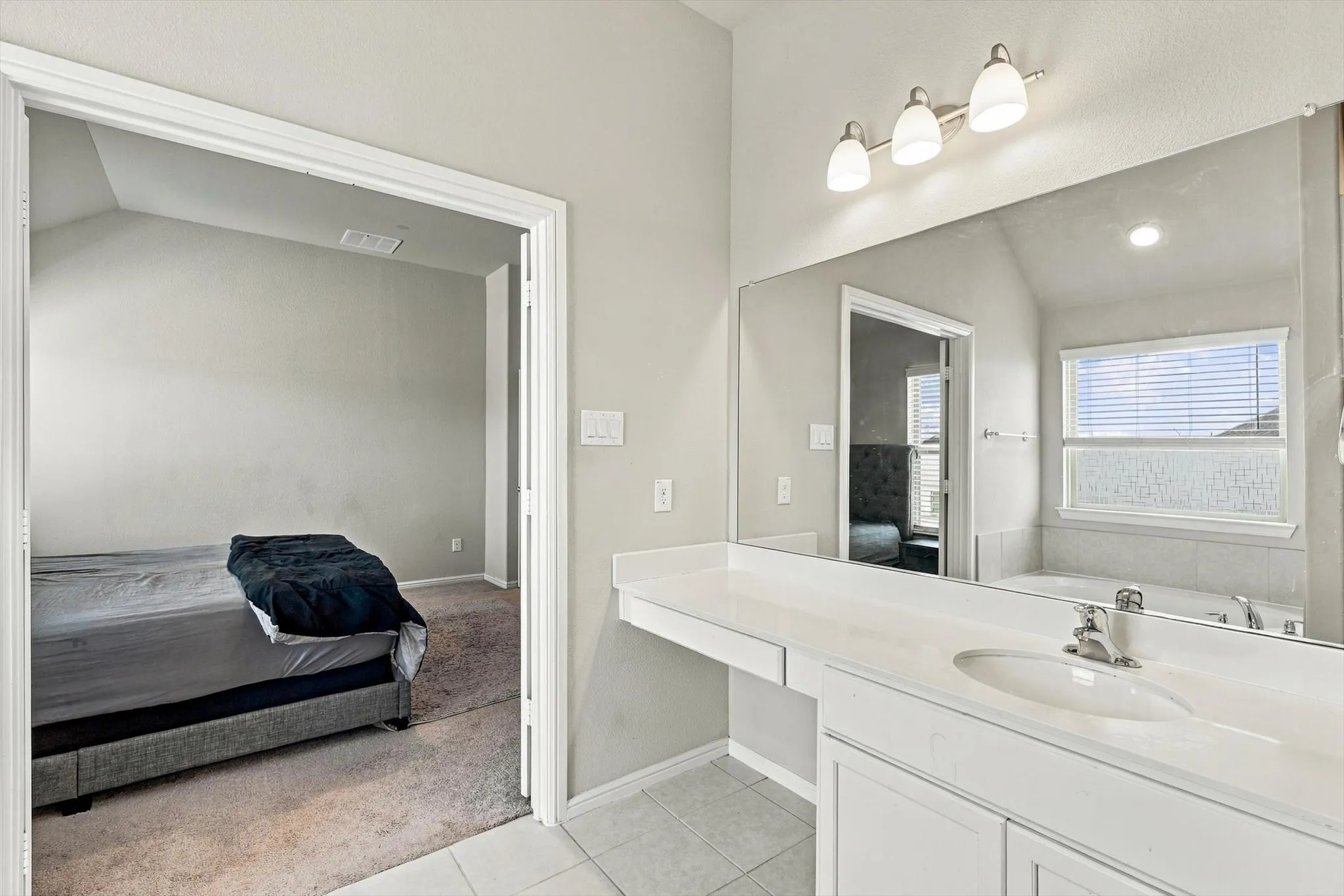 Vanity with integrated sink, extensive countertop space, wall-mounted mirror, and overhead lighting fixture