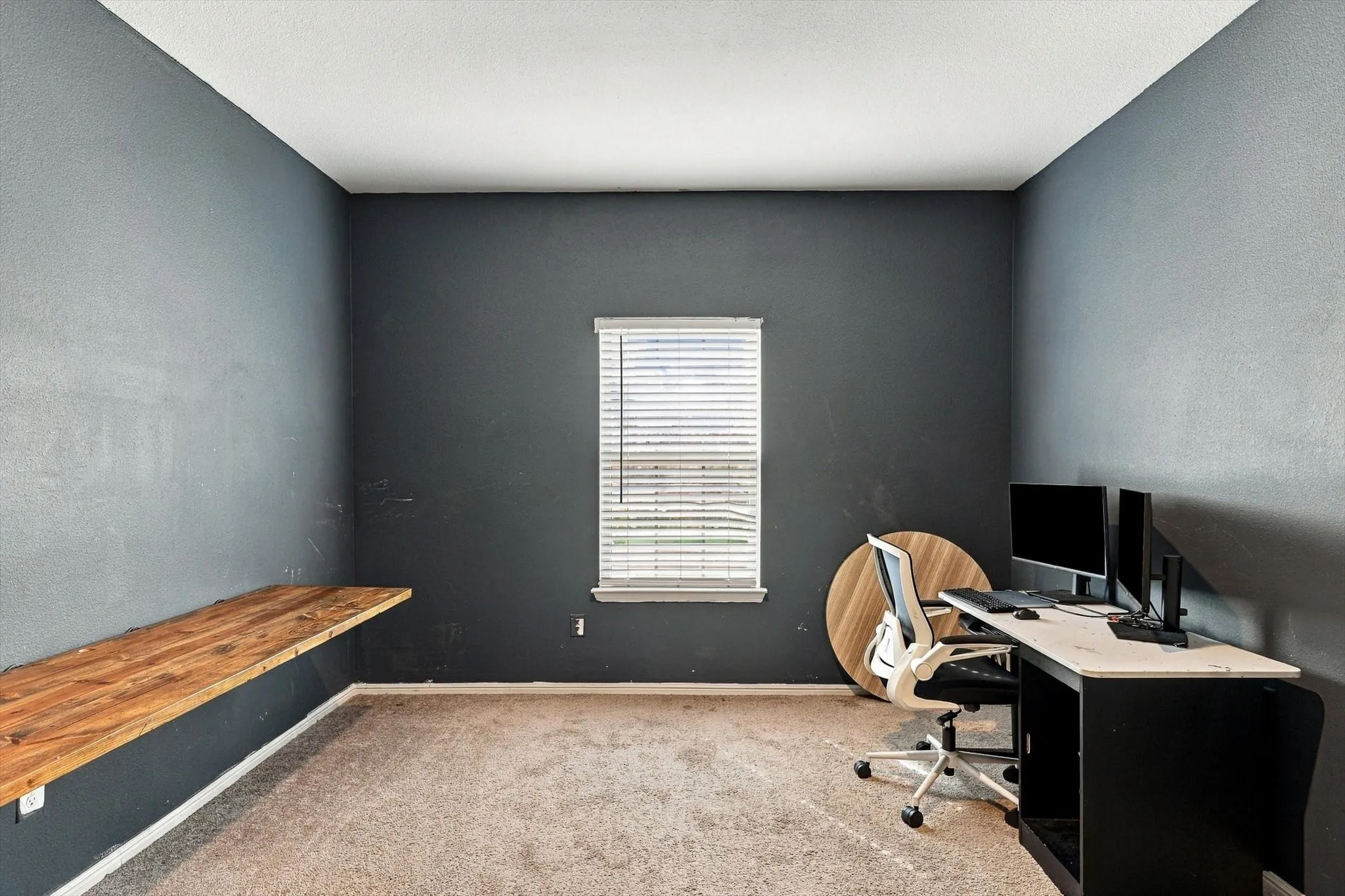 Built-in wood-finish shelving with dark wall paint and carpeted flooring