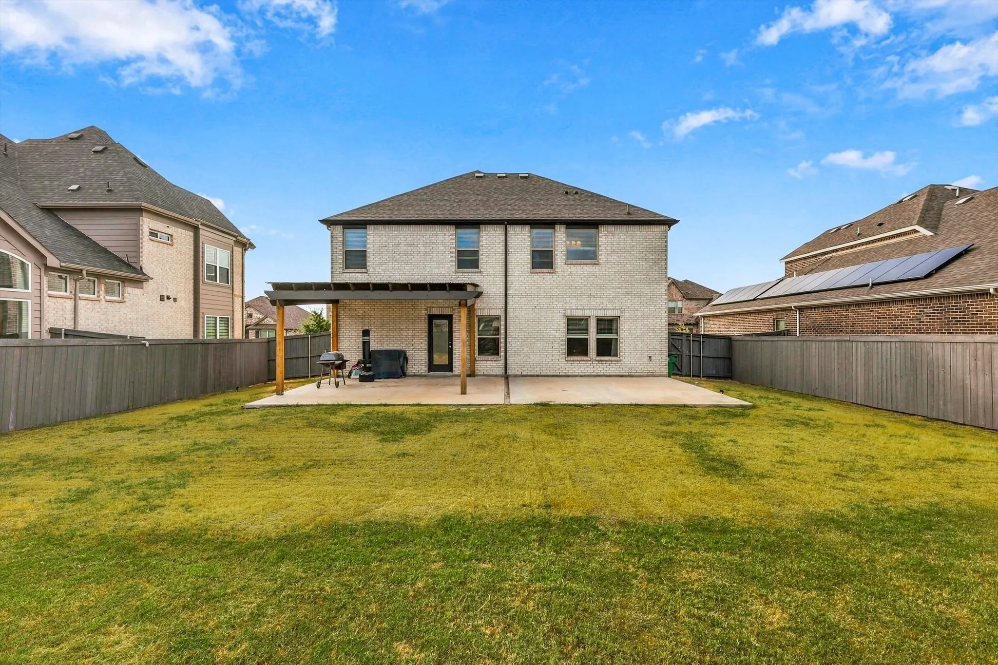 Expansive backyard featuring a manicured lawn, an extended concrete patio, and a covered pergola