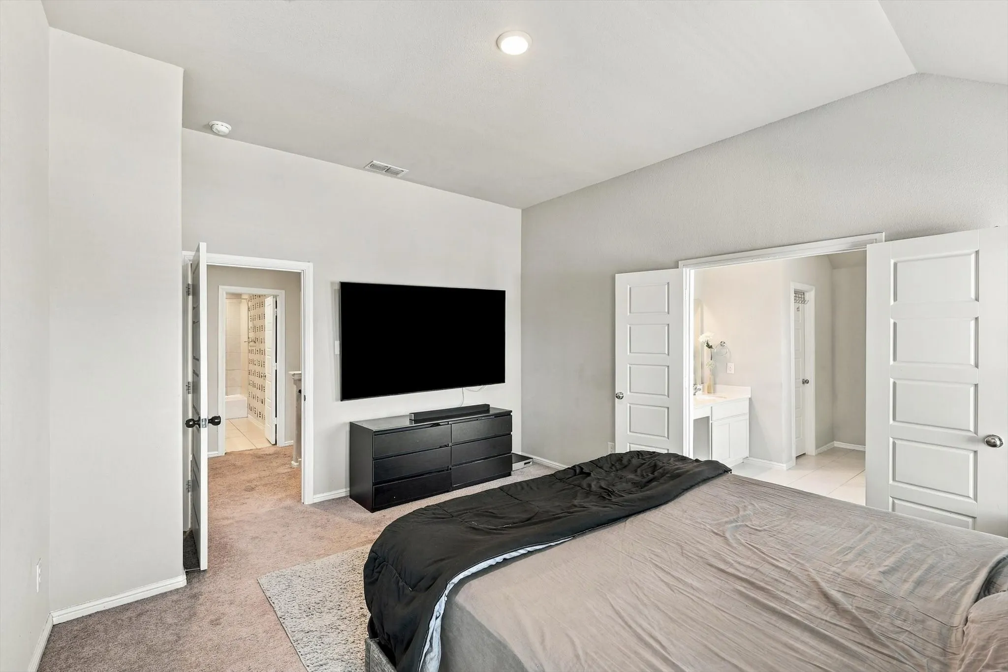 Vaulted ceiling with recessed lighting, carpet flooring, and white paneled doors