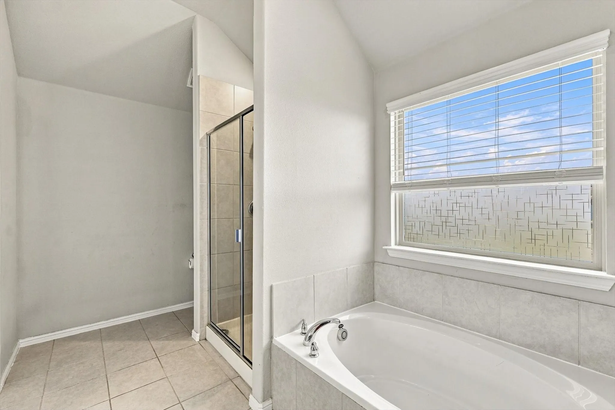 Soaking tub with tile surround, glass-enclosed shower, and tile flooring