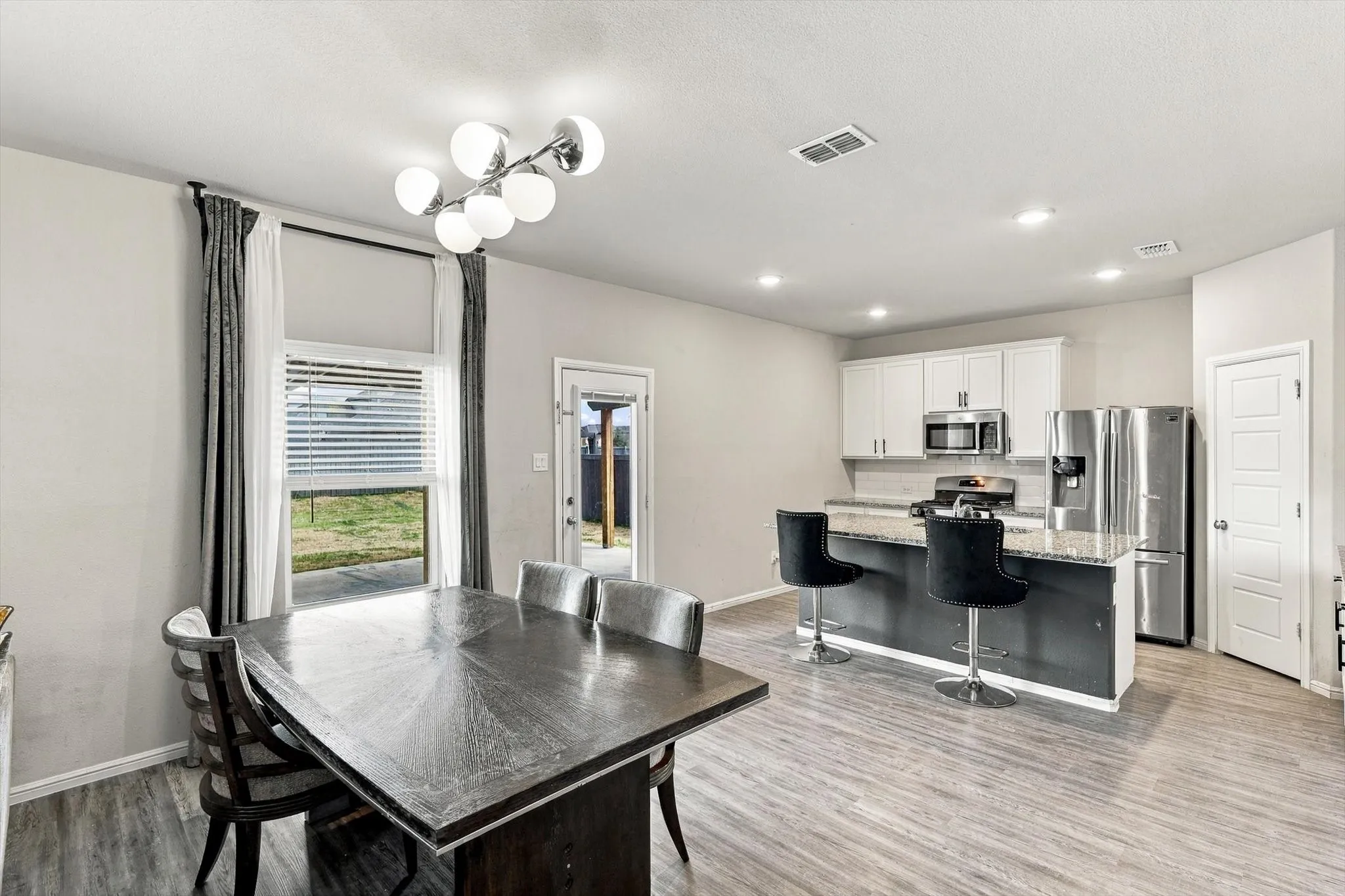 Open-concept living area featuring wood-finish flooring, a modern chandelier, and recessed lighting