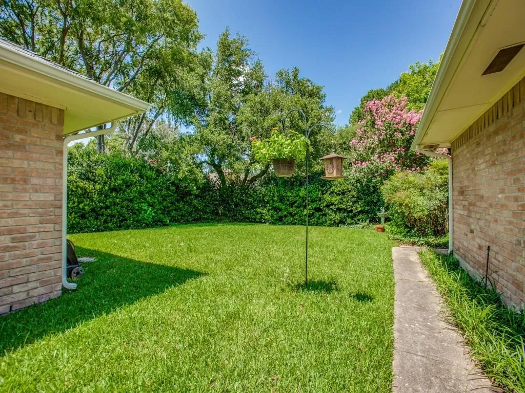 Expansive grassy area bordered by established trees and shrubs