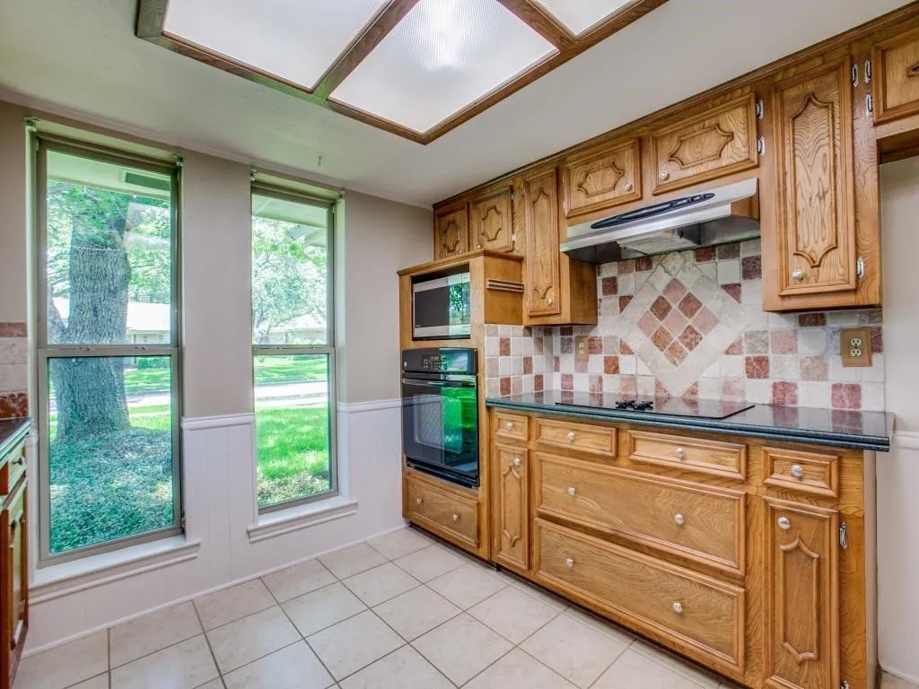 Oak cabinetry with paneling, built-in microwave, and double oven