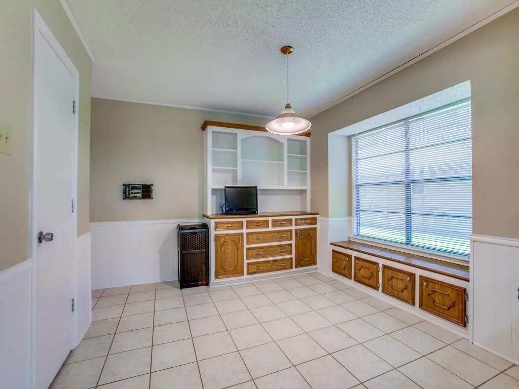 Tile flooring, built-in cabinetry with open shelving, built-in window seating with storage, and a pendant light fixture