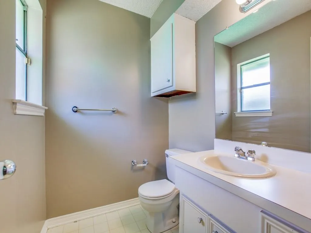 White vanity with integrated sink, chrome faucet, and mirrored wall