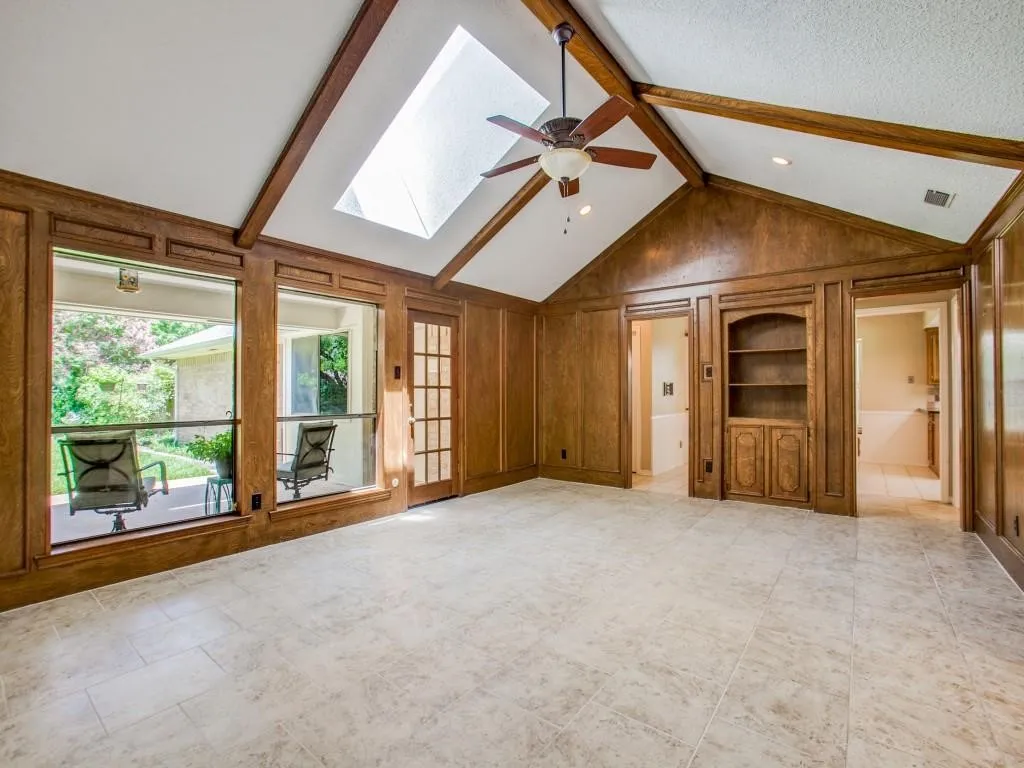 Vaulted ceiling with exposed wood beams, skylight, and ceiling fan