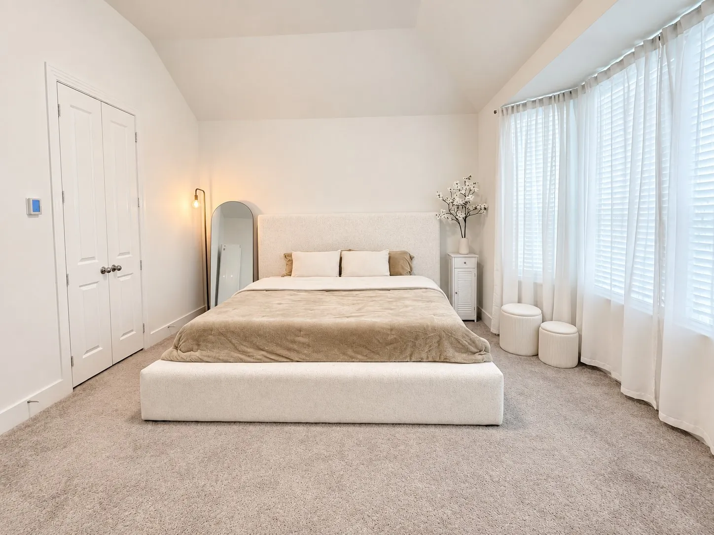 Vaulted ceiling, bay window, light-colored carpeting, and double-door closet