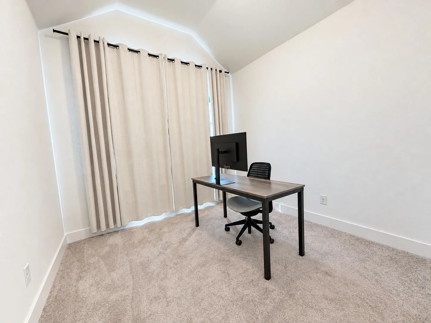 Vaulted ceiling, neutral wall tones, full-height window treatments, and light-toned carpeting