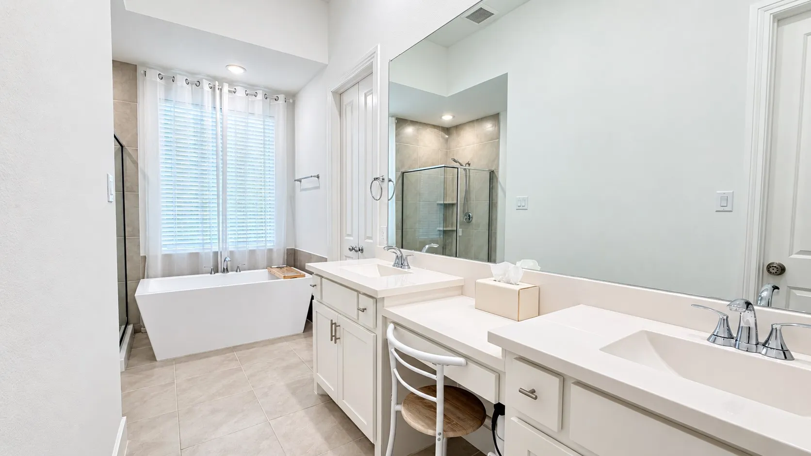 Dual vanity with light-colored countertops, white cabinetry, and polished chrome fixtures