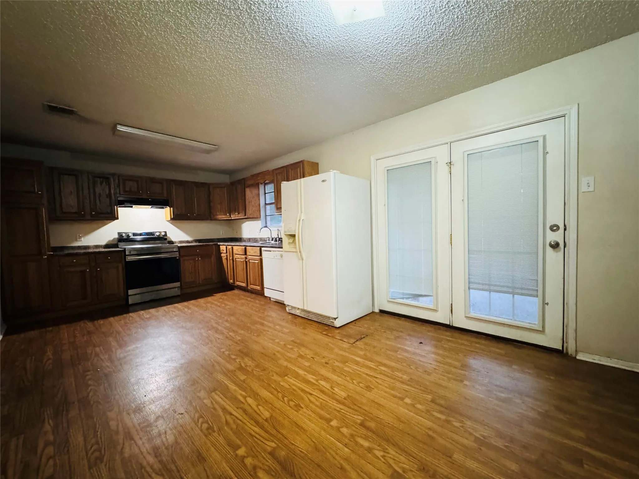Kitchen featuring wood-finish flooring, wood cabinetry, built-in stainless steel range, and double glass-paneled doors