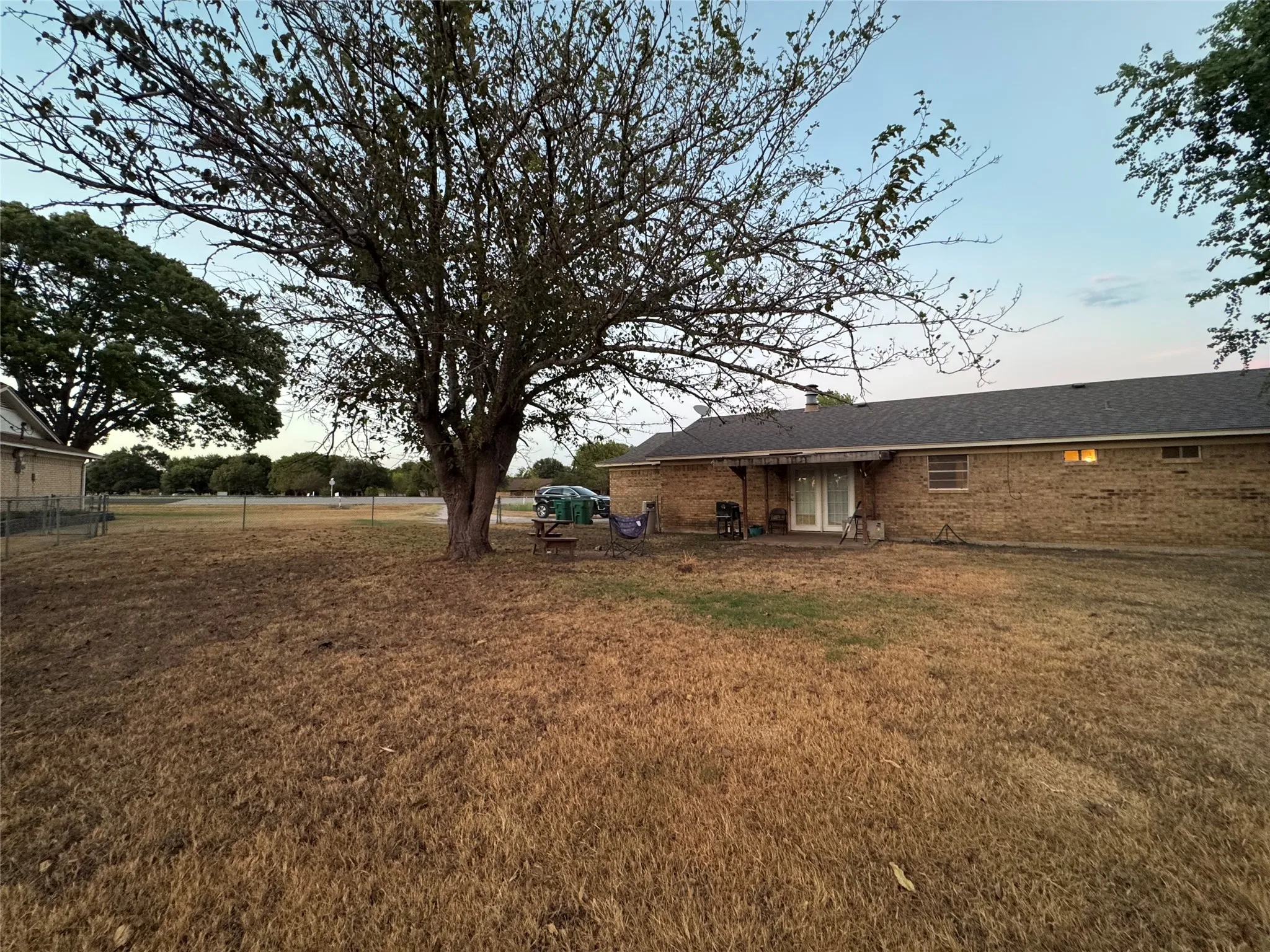 Brick exterior residence featuring a covered patio, double glass patio doors, and a mature tree