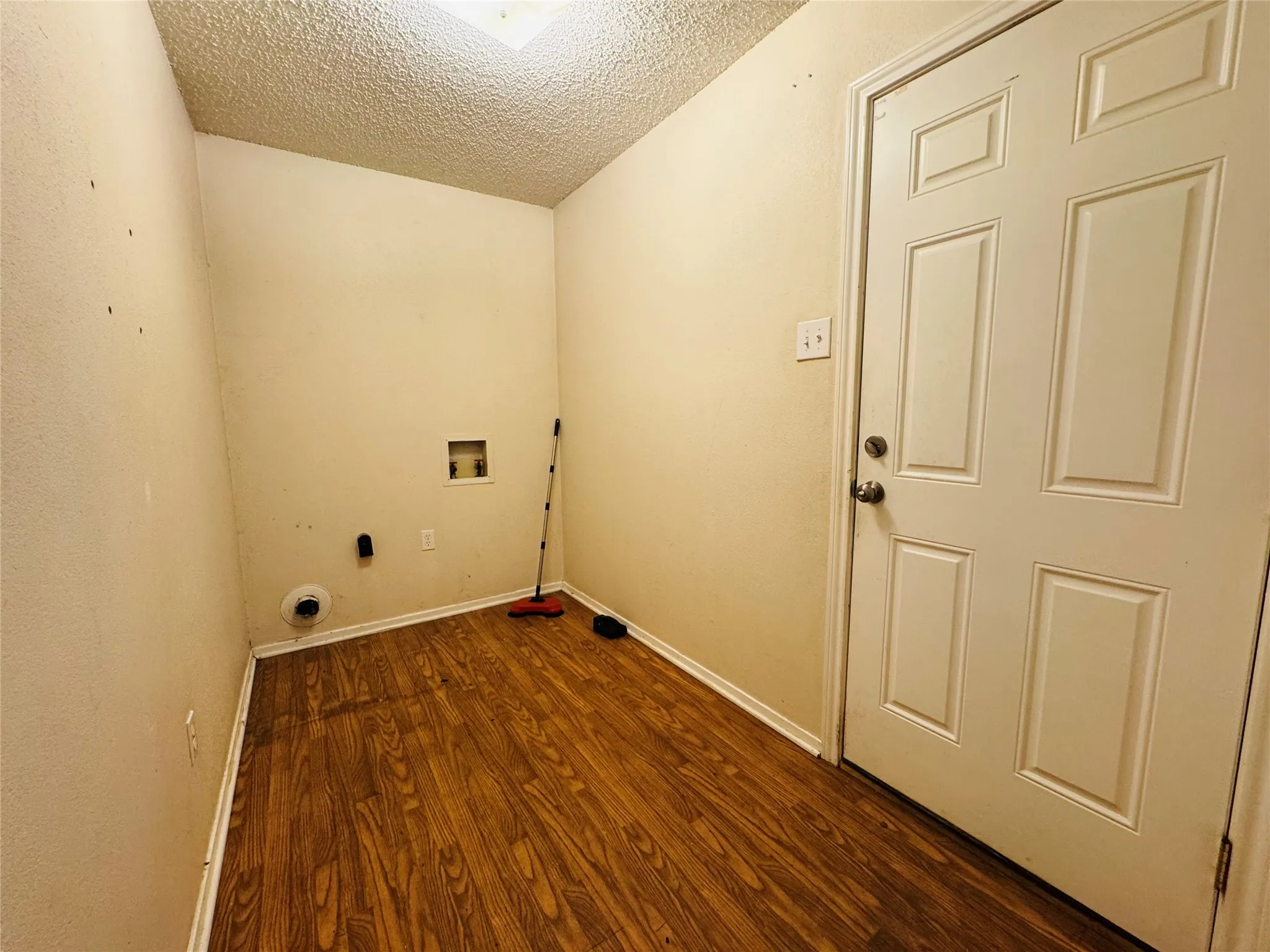 Utility room with wood-finish flooring, a paneled door, and ceiling lighting