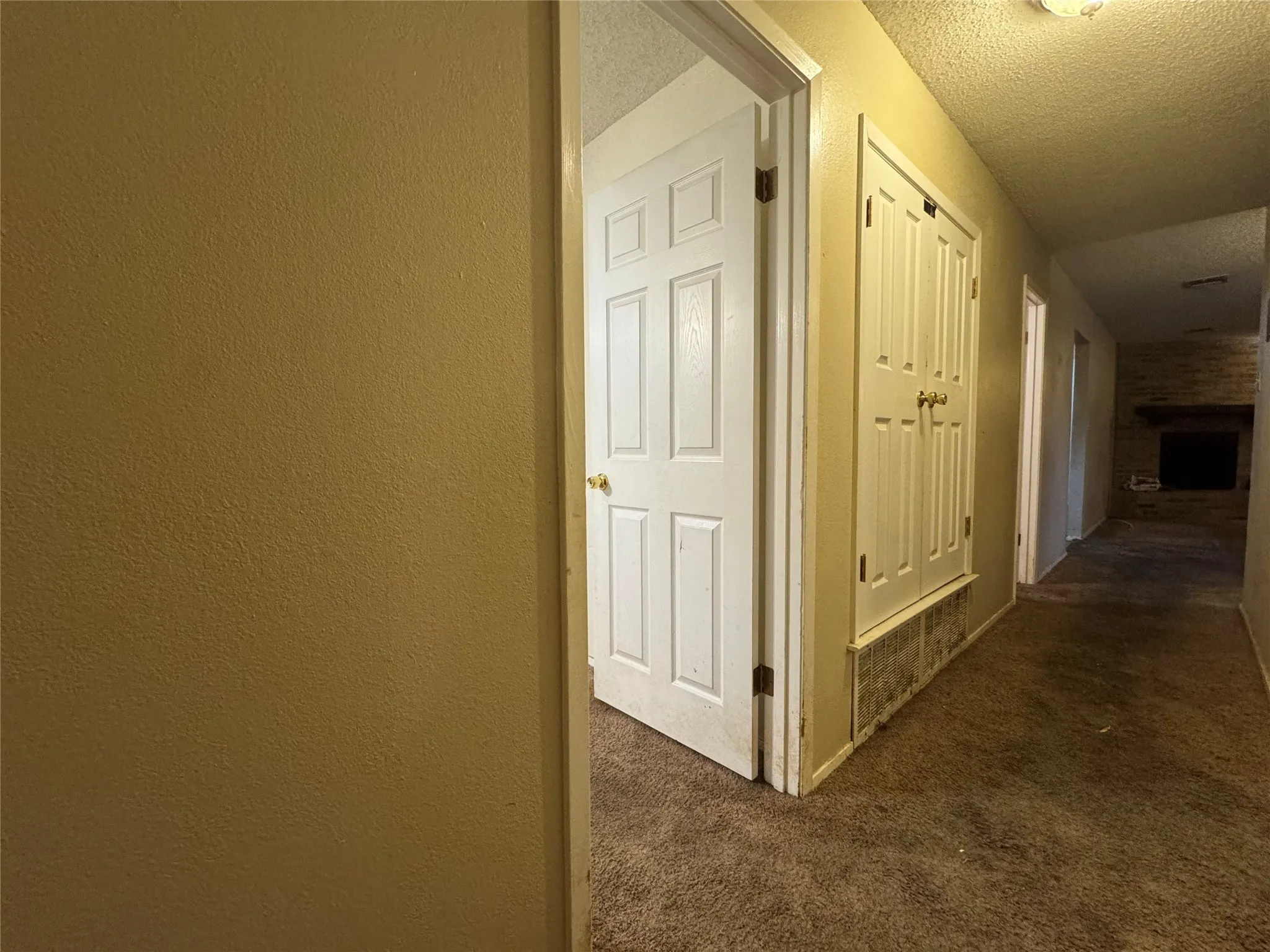 Textured walls, carpeted flooring, paneled doors, and a brick fireplace