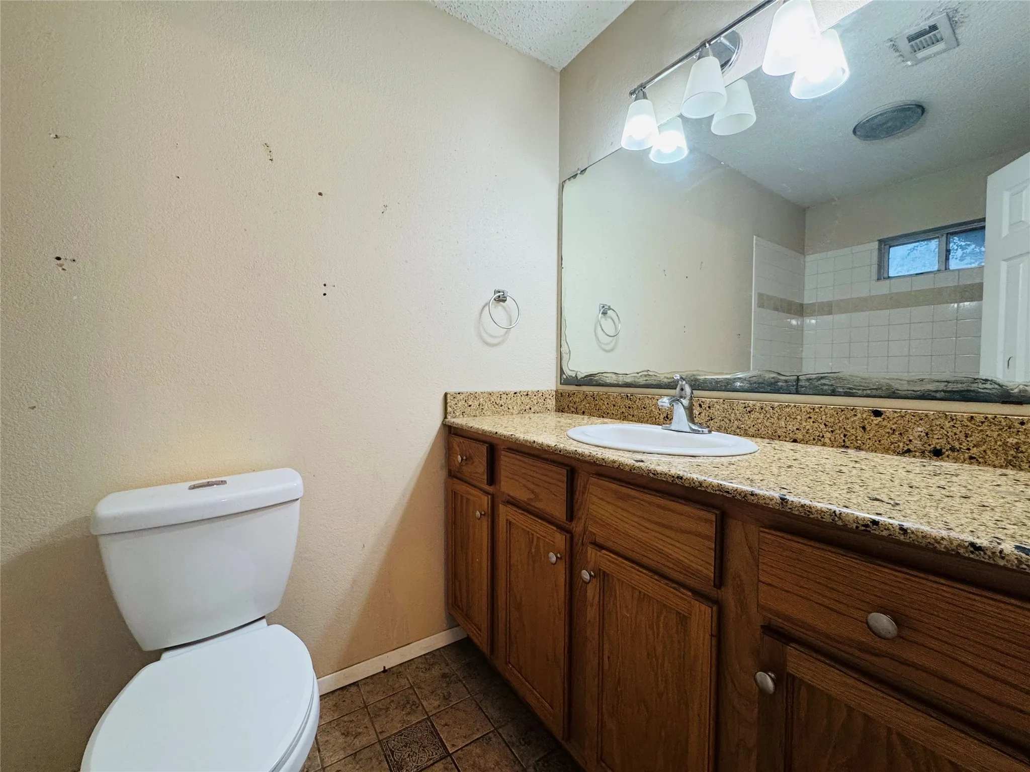 Vanity with a light-toned stone-finish countertop, undermount sink, and wood-finish cabinetry
