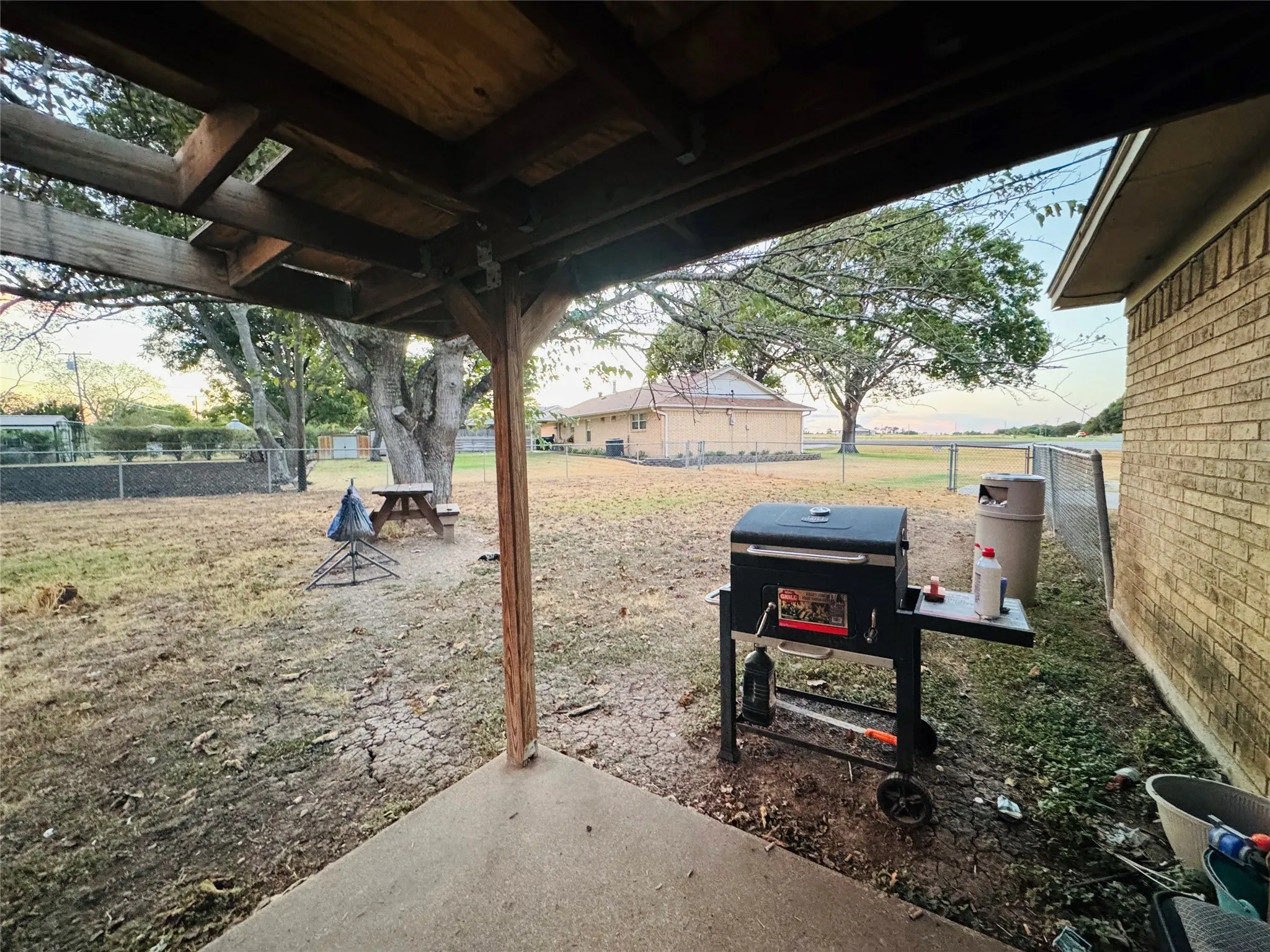 Covered patio with a concrete surface, supported by a wooden beam