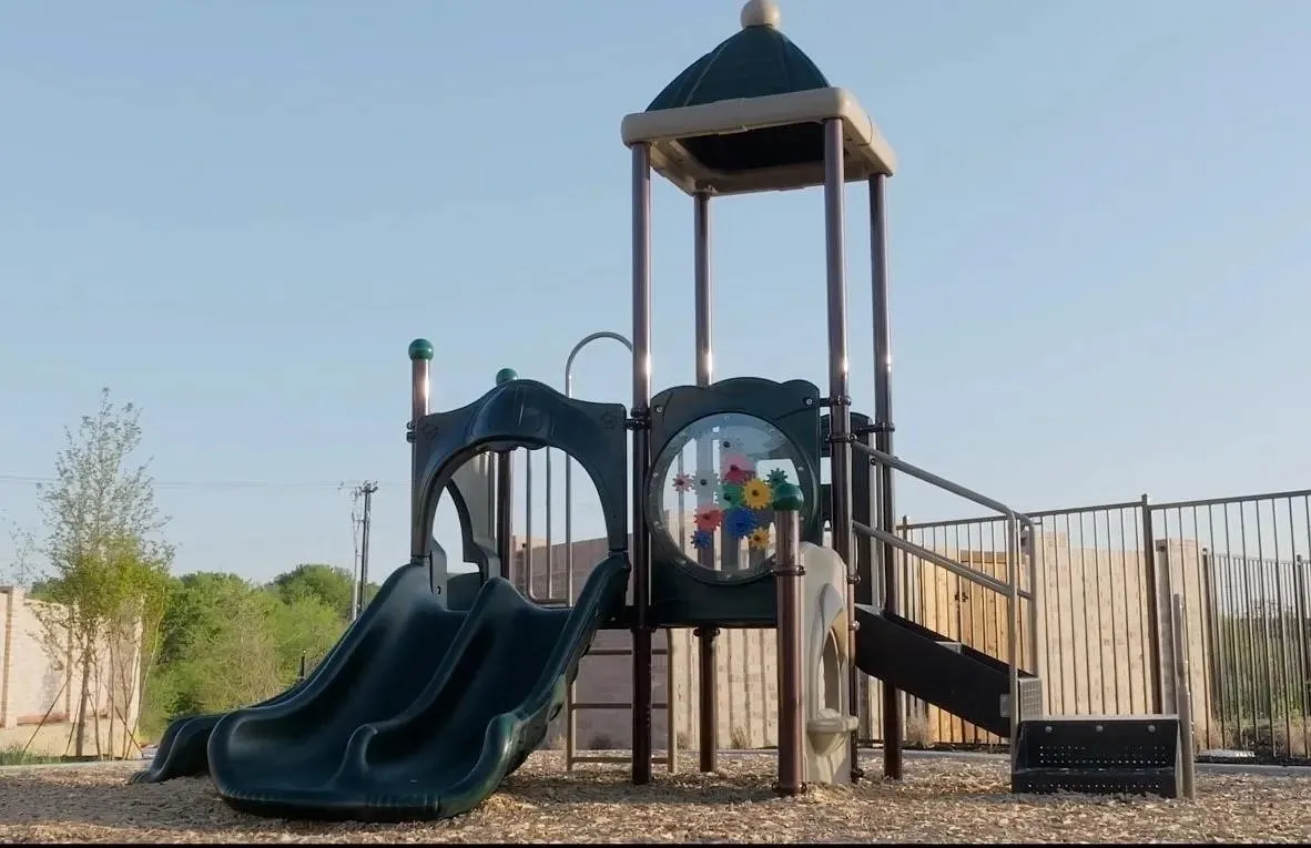 Playground structure featuring a slide, climbing stairs, and a decorative panel with colorful gears