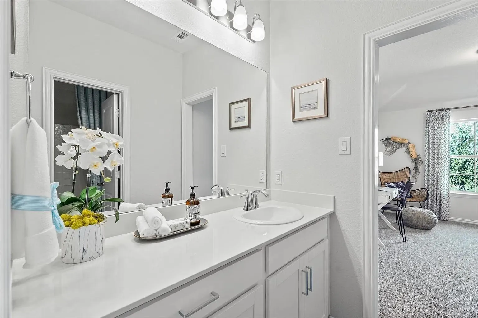 White vanity with integrated sink, polished chrome faucet, and overhead three-bulb vanity lighting