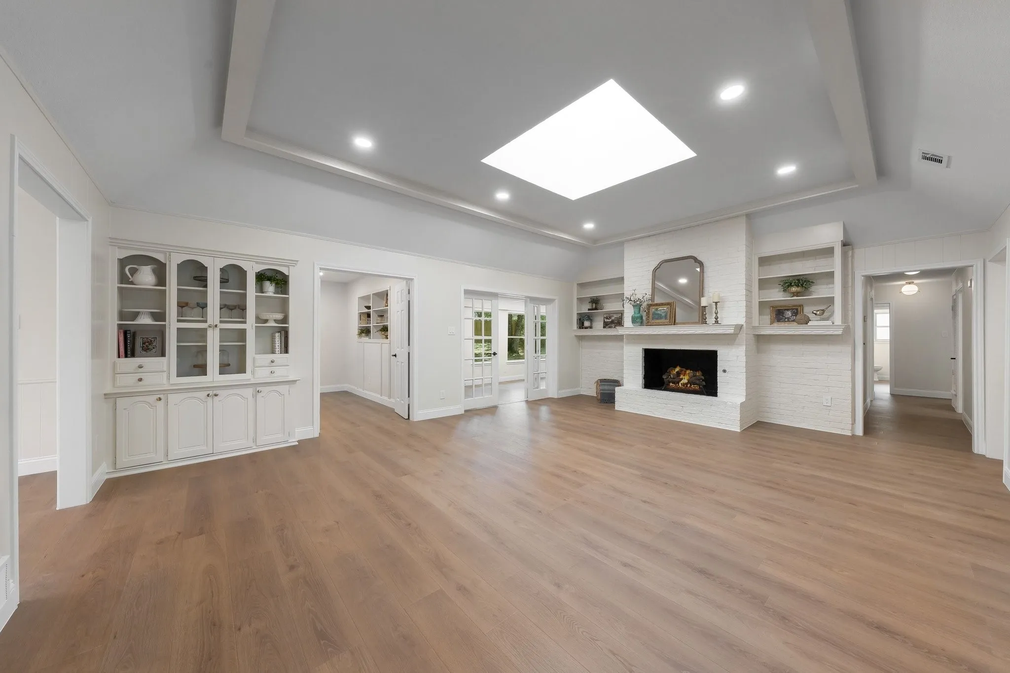 Wood-finish flooring, recessed lighting, and a skylight illuminate this living space
