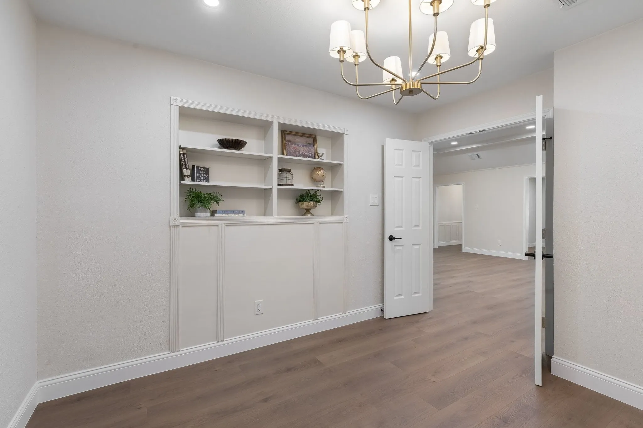 Built-in shelving with recessed lighting, a modern chandelier