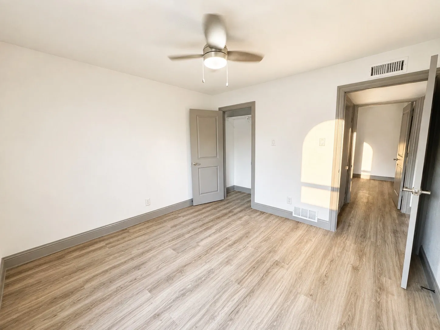 Wood-finish flooring, neutral wall tones, ceiling fan with integrated lighting, and a closet with bi-fold doors