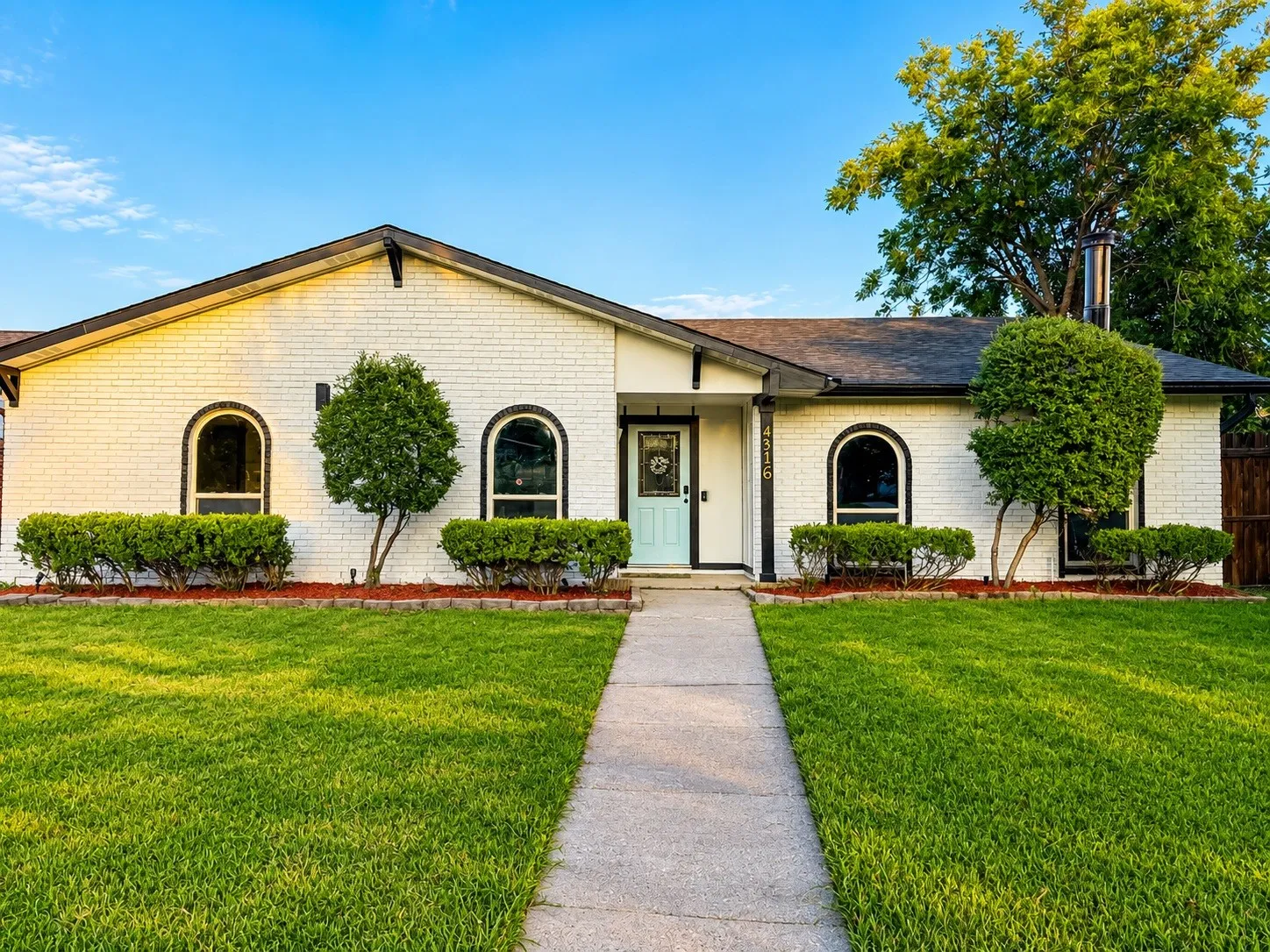 White brick exterior with a light blue entry door, featuring arched windows and dark trim