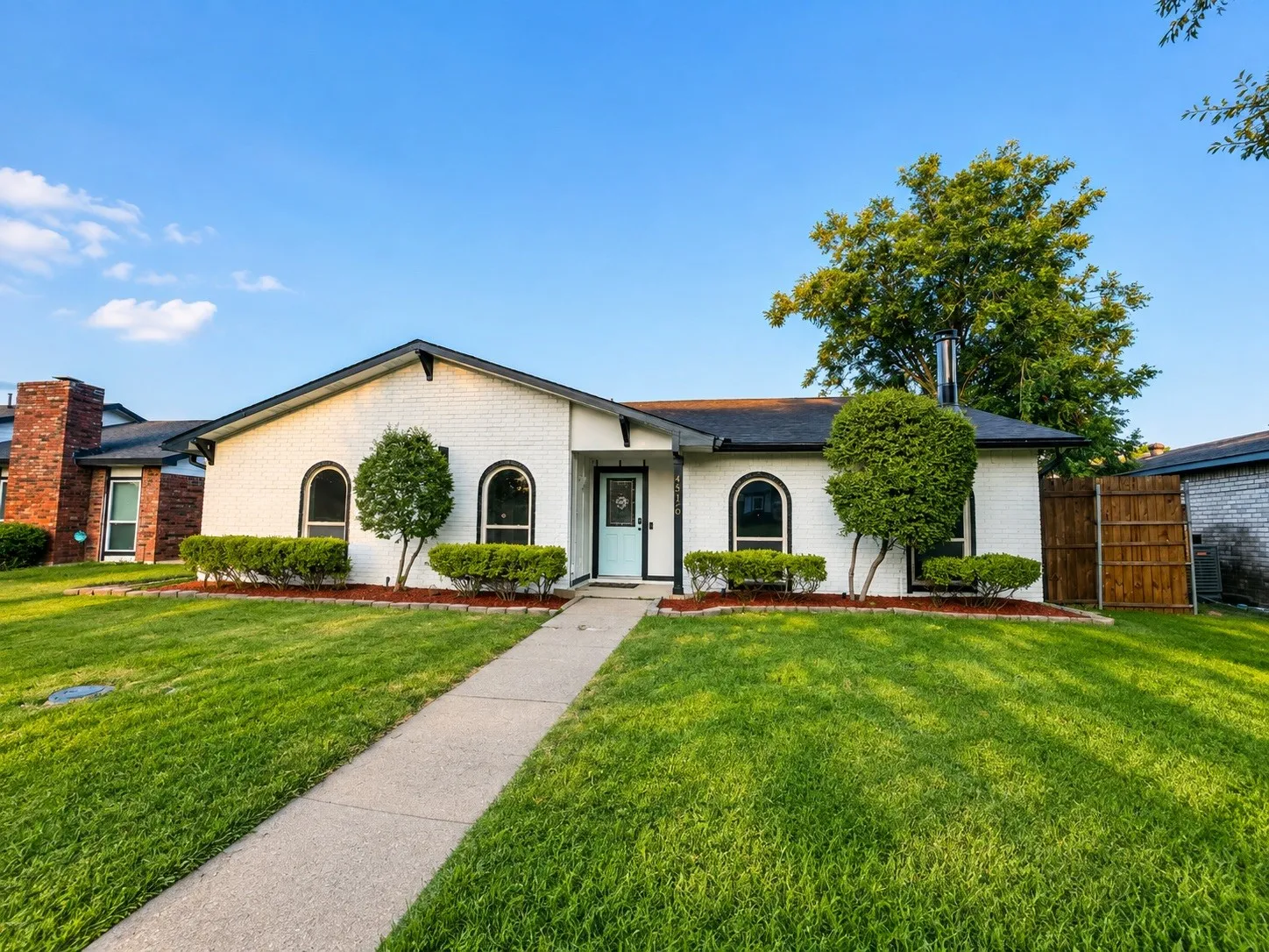 White brick exterior with black trim, arched windows, and a light blue front door