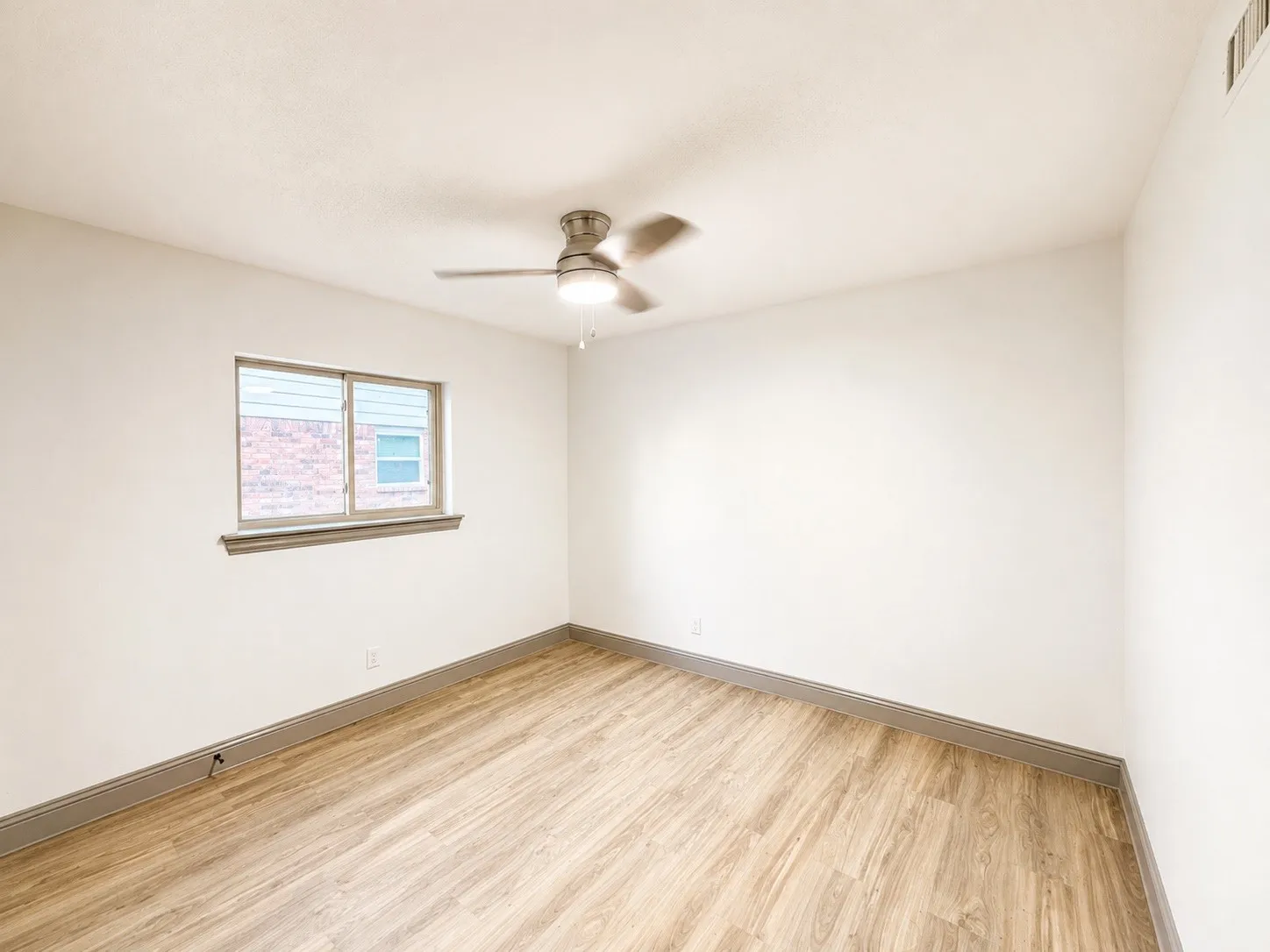 Wood-finish flooring, ceiling fan with integrated lighting, and a double-pane window