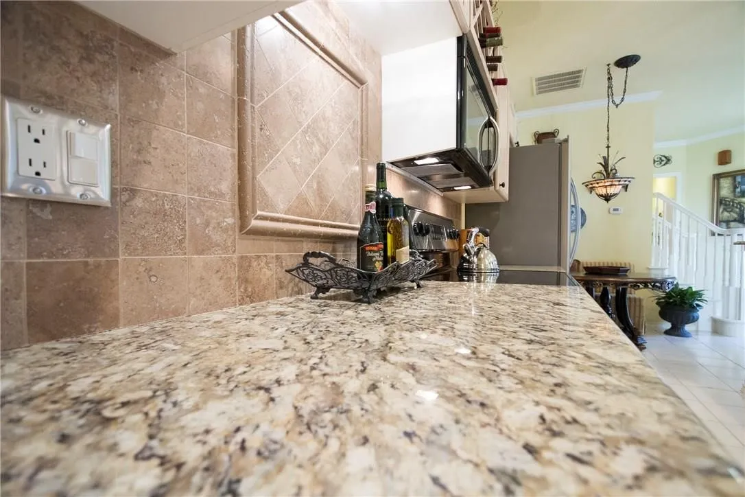 Stone countertop with integrated microwave, tile backsplash with decorative inset, and a built-in wine rack