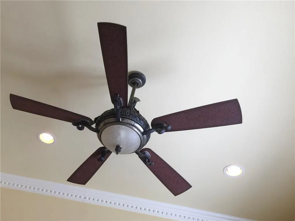 Decorative ceiling fan with an integrated light fixture, recessed lighting, and crown molding details