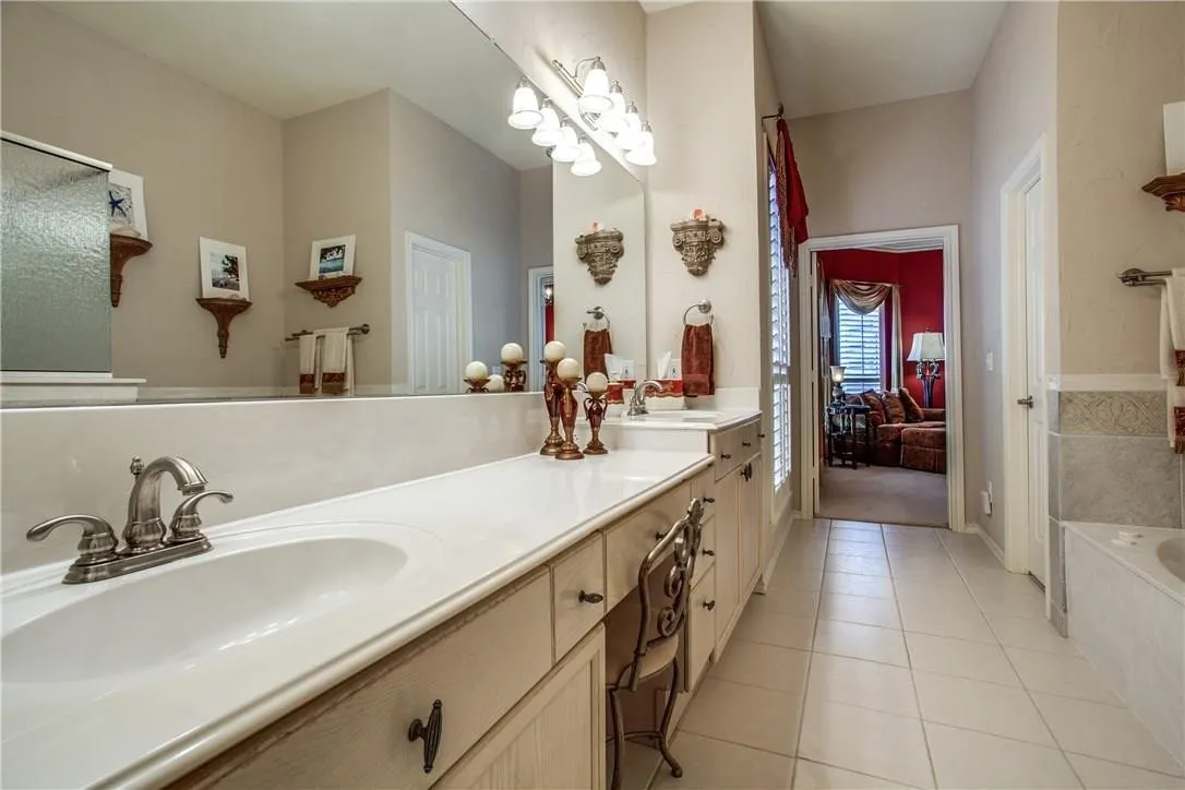Double vanity with integrated sinks, brushed nickel fixtures, light wood-finish cabinetry, and a large wall-mounted mirror