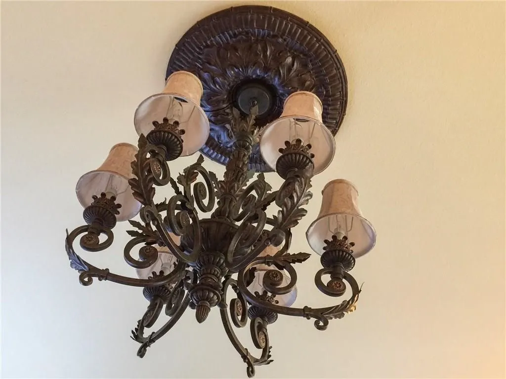 Ornate bronze chandelier with decorative ceiling medallion, featuring frosted glass shades and fabric accents