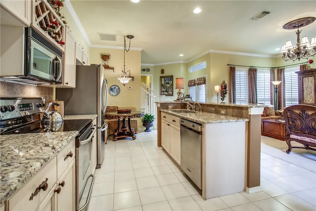 Well-appointed kitchen featuring granite countertops, stainless steel appliances, white cabinetry with decorative hardware, and tile flooring