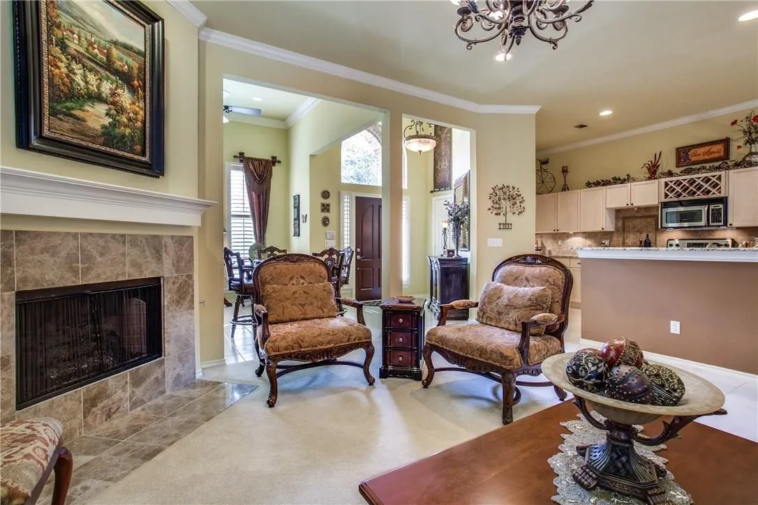 Living area featuring a tile-surround fireplace, crown molding, and an open-concept design to the kitchen