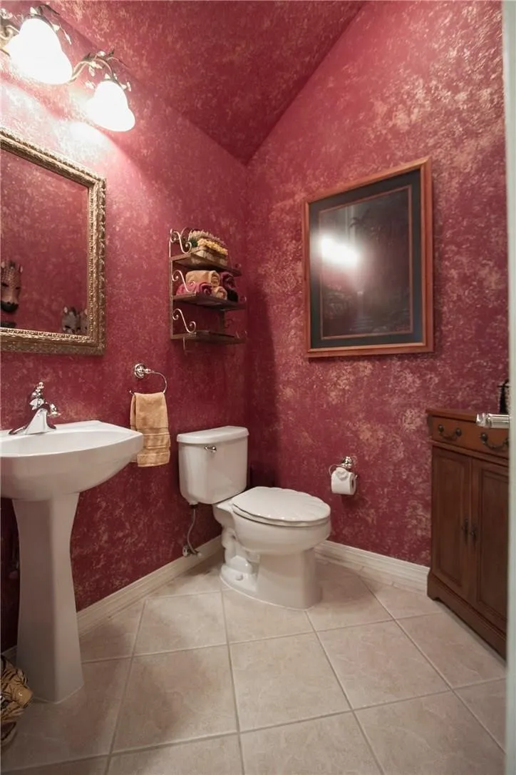 Pedestal sink with chrome fixtures, tiled flooring, built-in vanity cabinet, and wall-mounted light fixture