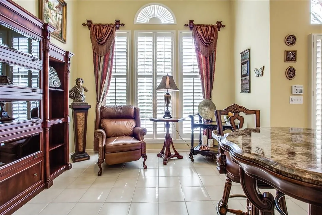Tile flooring, built-in shelving, arched transom window, window shutters, and a stone-finish countertop