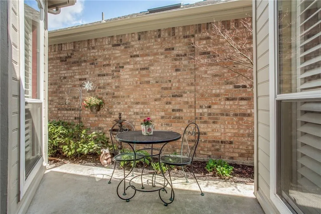 Enclosed patio with brick wall surround, concrete flooring, and established plantings