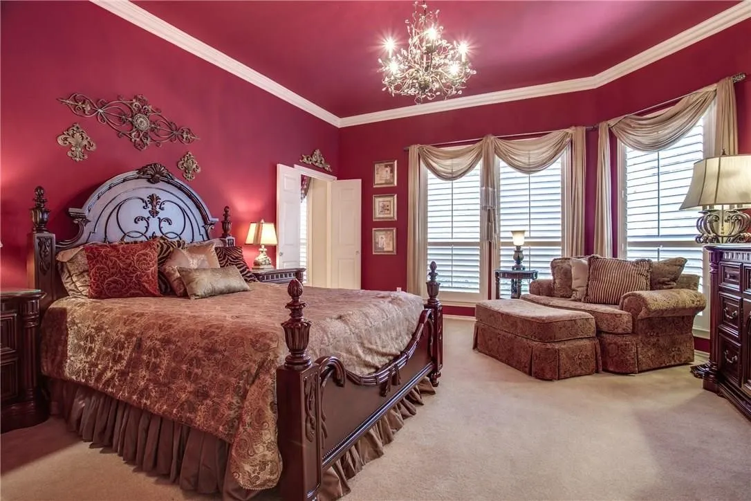 Recessed bay window with plantation shutters, crown molding, chandelier, and carpeted flooring
