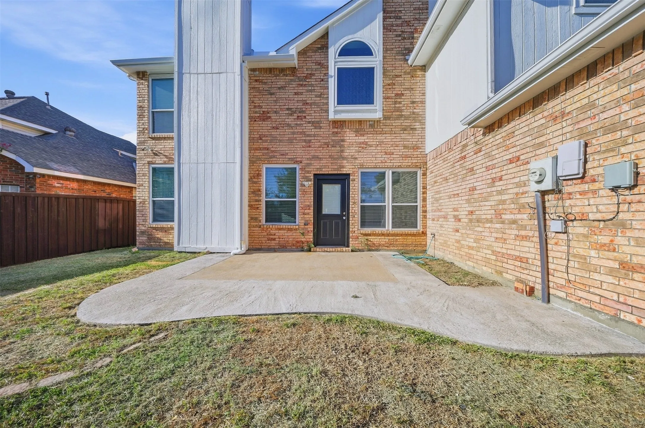 Expansive concrete patio with a brick exterior, white trim, and a prominent chimney feature