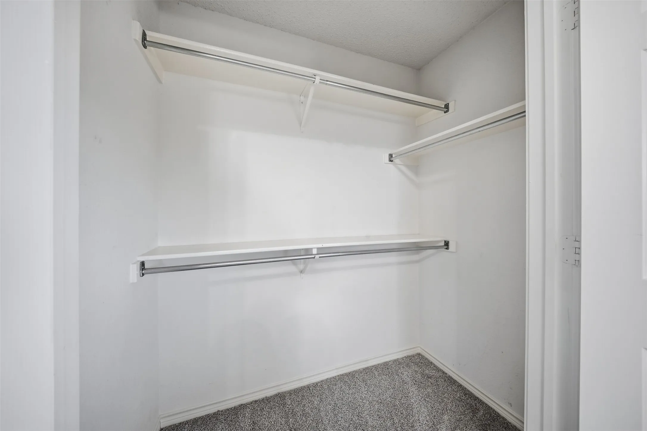 White walls with two levels of shelving and hanging rods