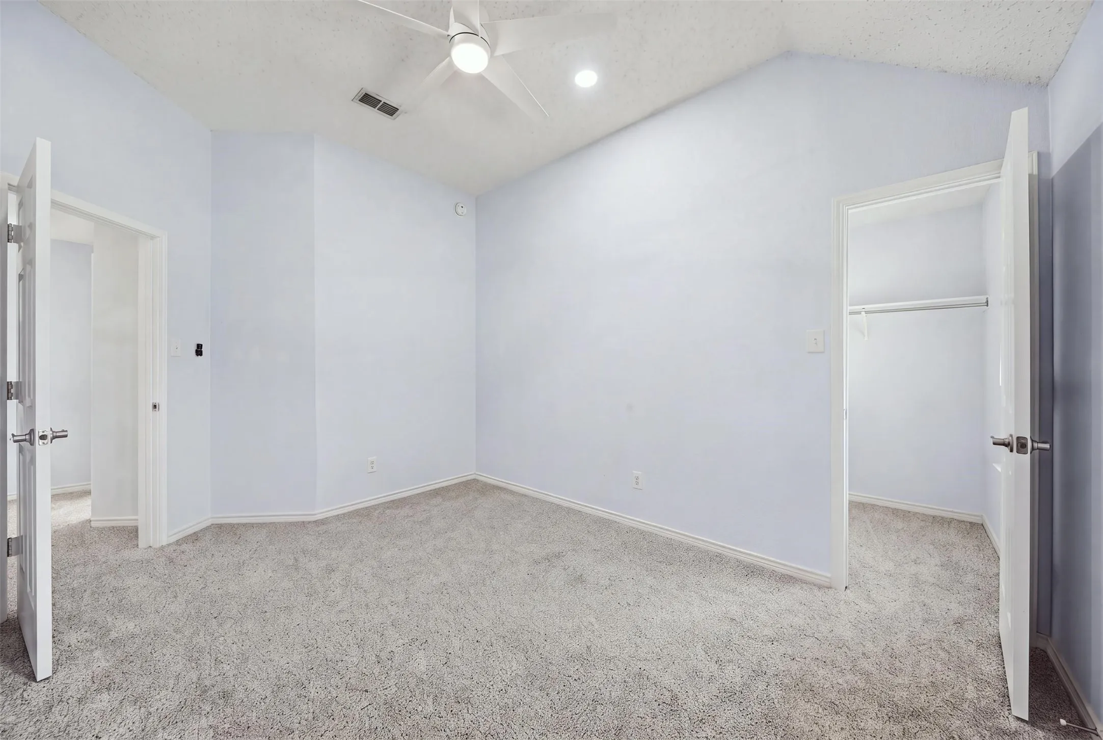 Vaulted ceiling with an integrated ceiling fan, recessed lighting, and soft grey carpeting
