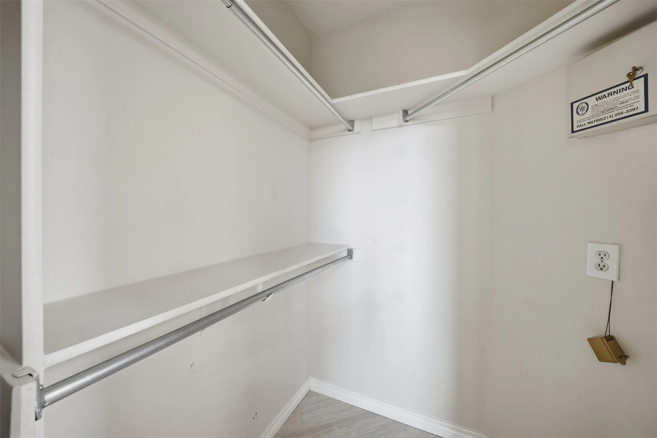 White-painted walls with crown molding, equipped with upper and lower shelving, and a metal hanging rod