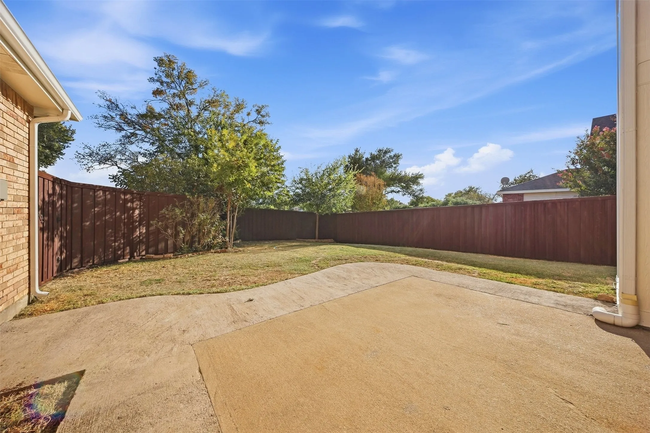 Expansive backyard featuring a concrete patio, a privacy fence, and a grass lawn