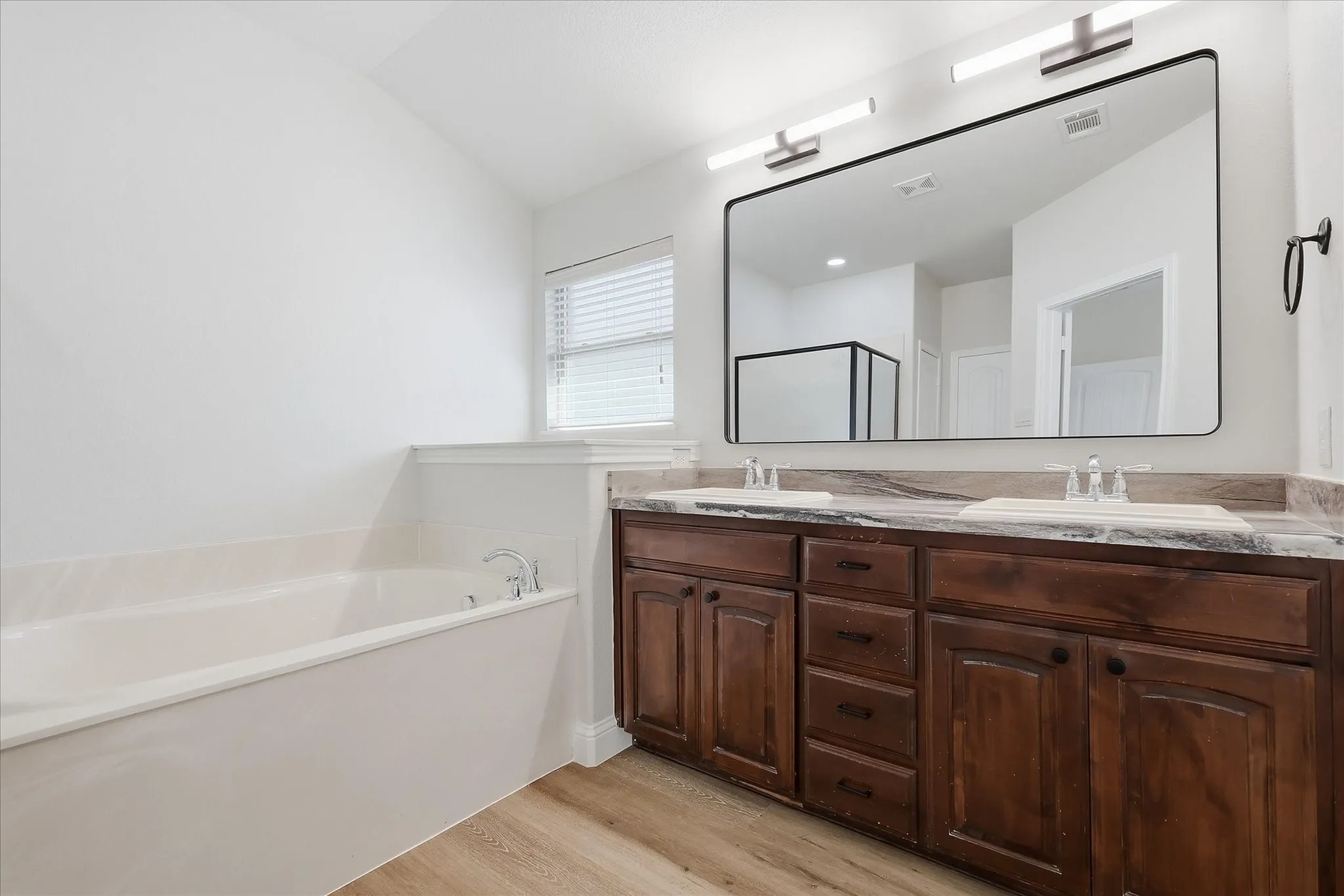 Dual sink vanity with dark wood cabinetry and integrated sinks, complemented by a large rectangular mirror