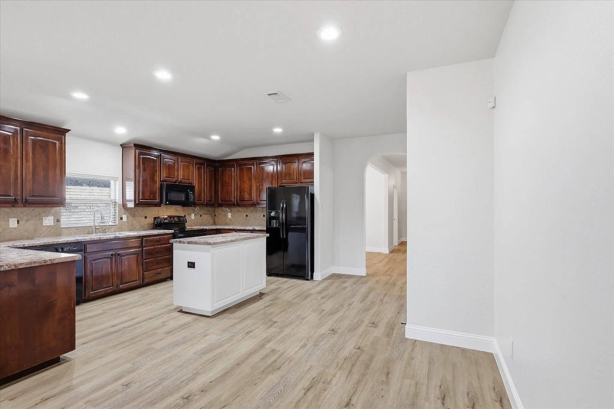 Kitchen featuring wood-finish flooring, dark wood cabinetry, and a white island