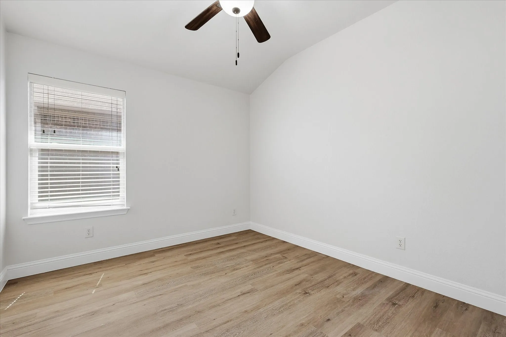 Vaulted ceiling, wood-finish flooring, ceiling fan, window with blinds