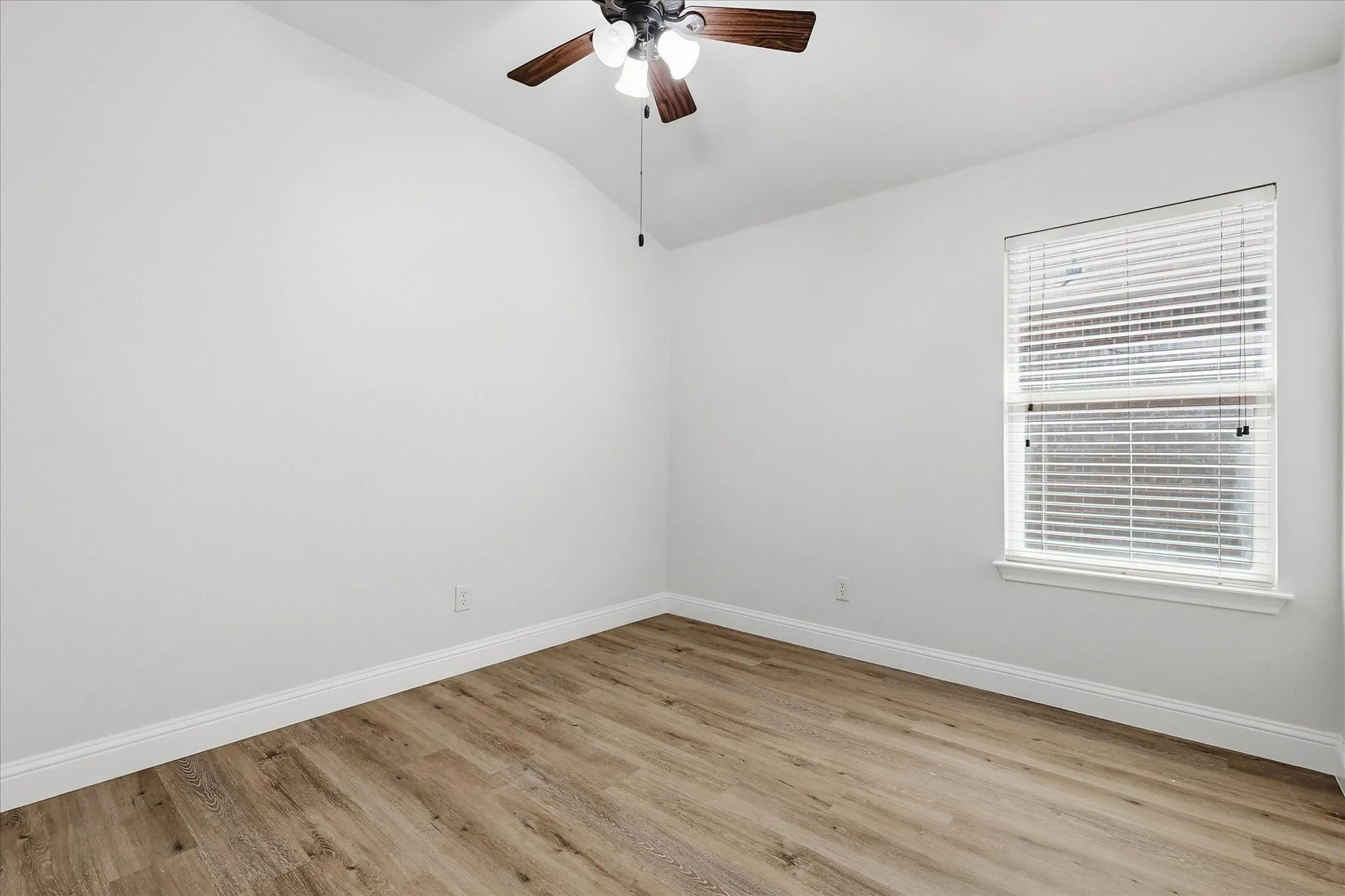 Vaulted ceiling, wood-finish flooring, ceiling fan with integrated lighting, single window