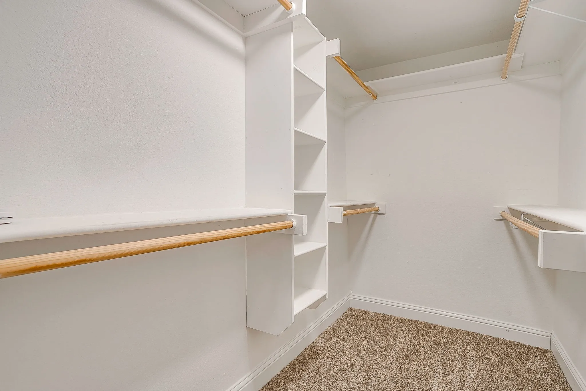 Built-in shelving, multiple hanging rods, and carpeted flooring