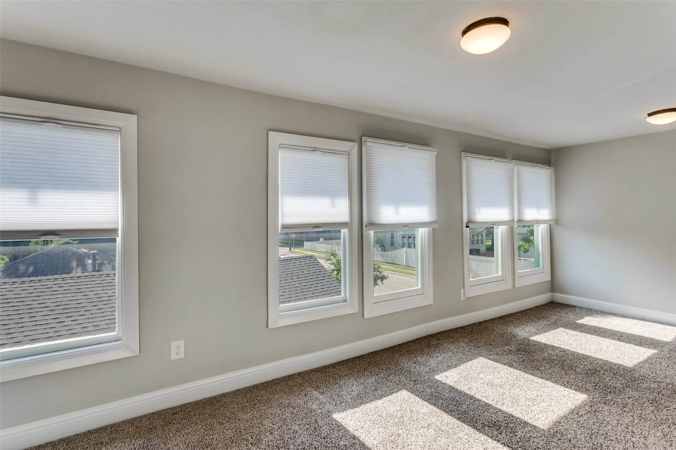 Multiple large windows with white trim, neutral-toned walls, recessed lighting, and textured carpeting